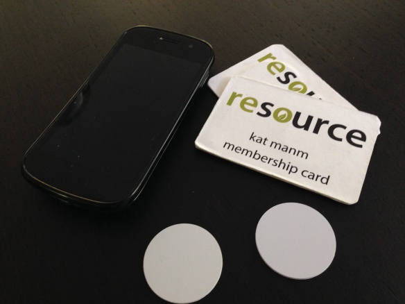 A phone, two mock-up membership cards with RFID tags embedded, and two raw RFID tags